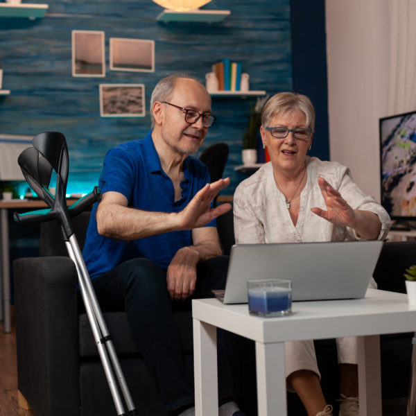 seniors waving at video call camera on laptop